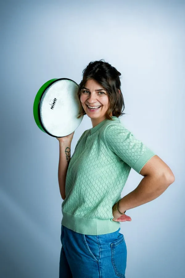 Porträt von Lisa, sie hält eine grüne Handtrommel neben den Kopf